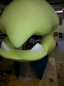 A large green monster with white teeth on top of it.