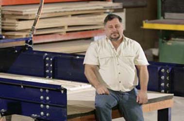 A man sitting on top of a bench in front of stacks.