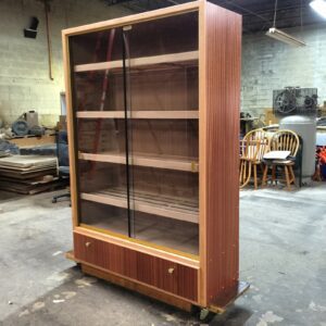A large wooden bookcase with glass doors and drawers.