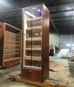 A tall wooden cabinet with glass doors in an empty room.