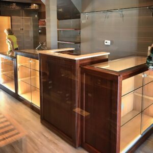 A wooden counter with glass shelves and lights.