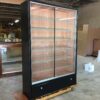 A large black cabinet with glass doors in the middle of a warehouse.