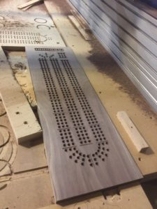 A cribbage board is being made with holes.