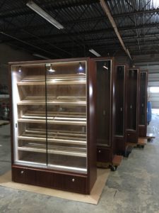 A row of refrigerators in a warehouse with glass doors.