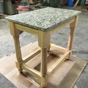 A table with granite top sitting on a piece of wood.