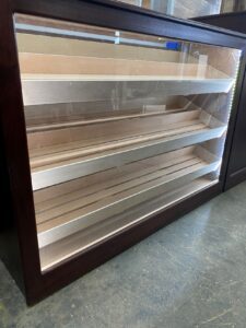 A wooden display case with three shelves and glass doors.