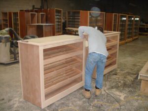A man working on a wooden shelf in an unfinished room.