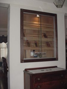 A mirror in the wall above a wooden cabinet.